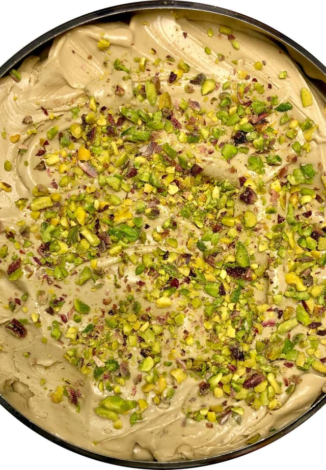 Pistachio gelato in a round pan, scattered with chopped pistachios