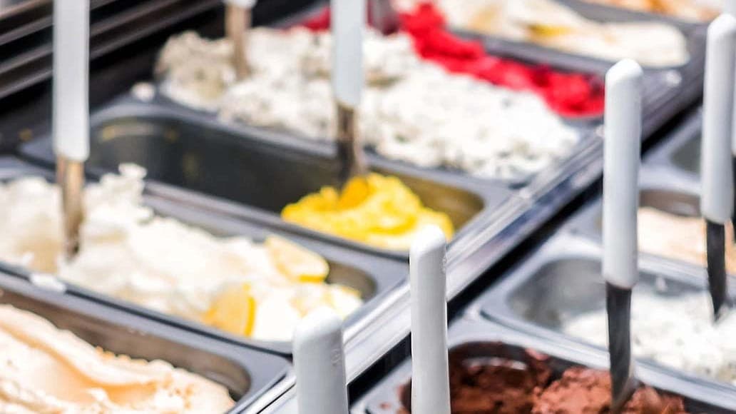 Open gelato trays with spatulas in the chilled display counter